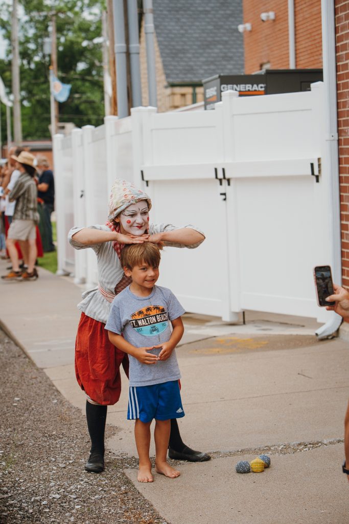 This is a photo of Emerald Kelley, the Clockwork Clown, posing with a kid at the 2024 French Heritage Festival.