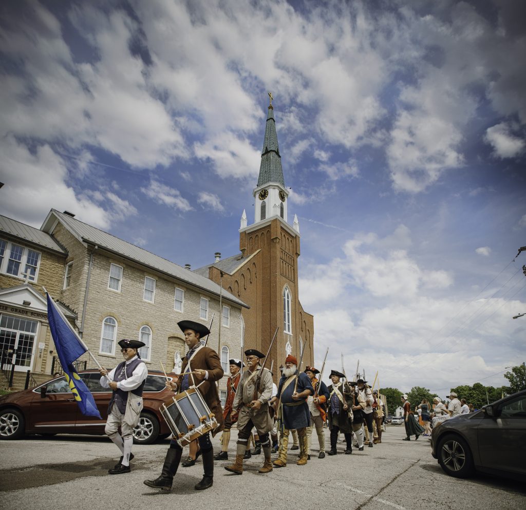 This is a photo of the Ste. Genevieve Militia lining up for the opening promenade of the 2024 French Heritage Festival. Local celeb Ronnie Rayfield is leading the charge with his drum.